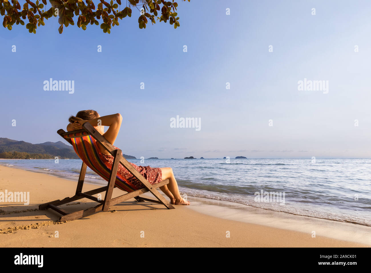 Mujer disfrutando de las vacaciones en la playa y relajarse en una hamaca cerca del mar, cálidos y soleados días de verano para descansar y tomar el sol Foto de stock