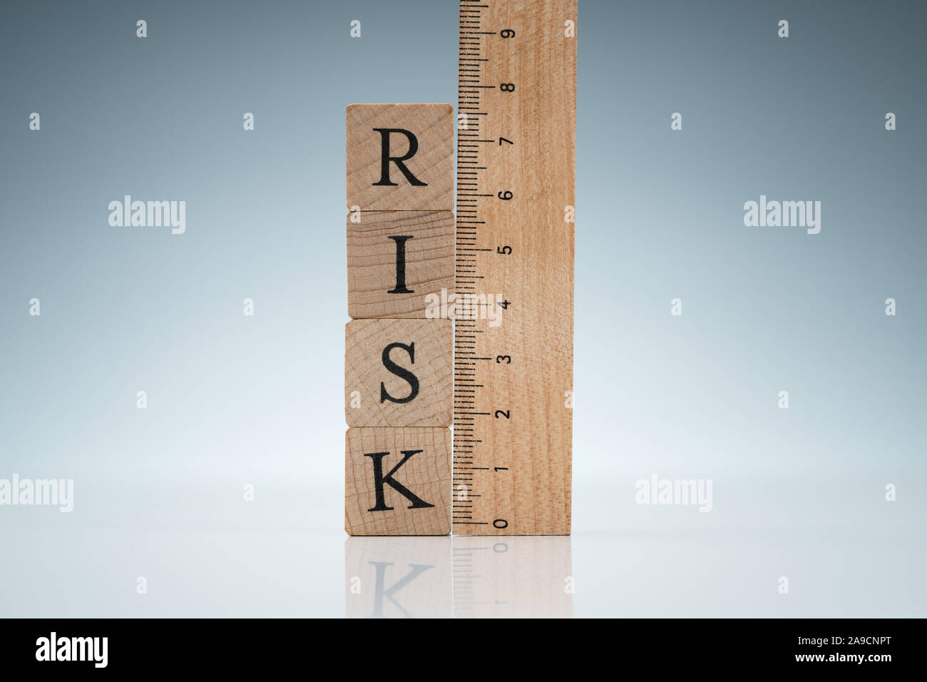 La palabra riesgo sobre bloques de madera apilados cerca de la regla en la mesa reflectante Foto de stock