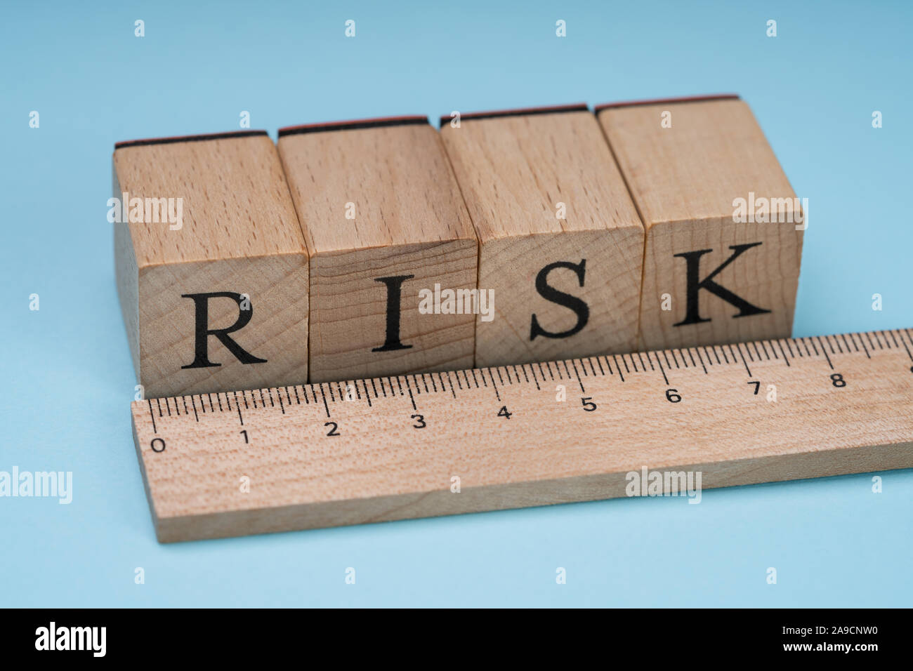 Close-up de un riesgo palabra sobre bloques de madera dispuestas detrás de la regla sobre fondo azul. Foto de stock