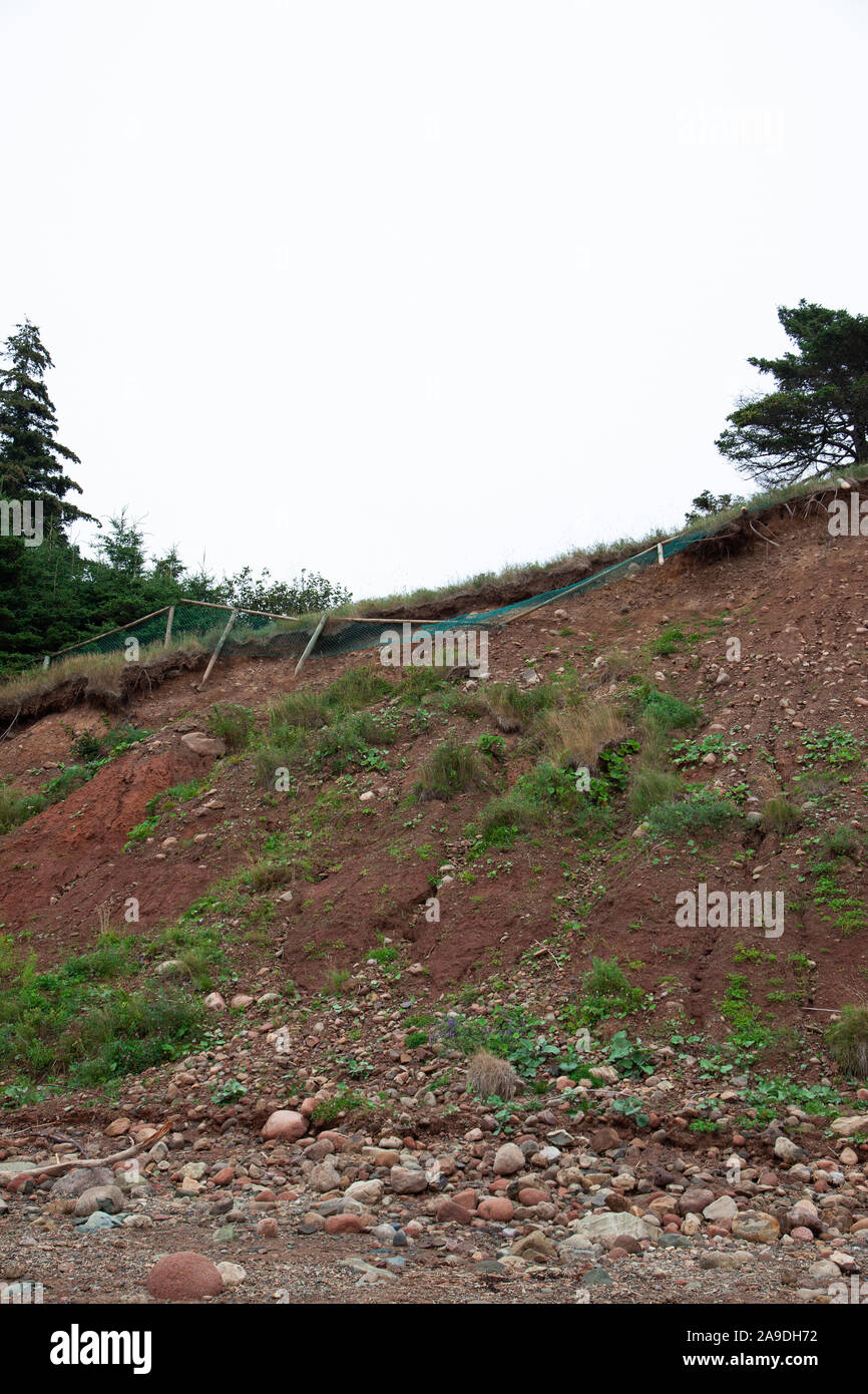 Valla de madera cayendo al lado de un acantilado erosionando banco debido al cambio climático Foto de stock