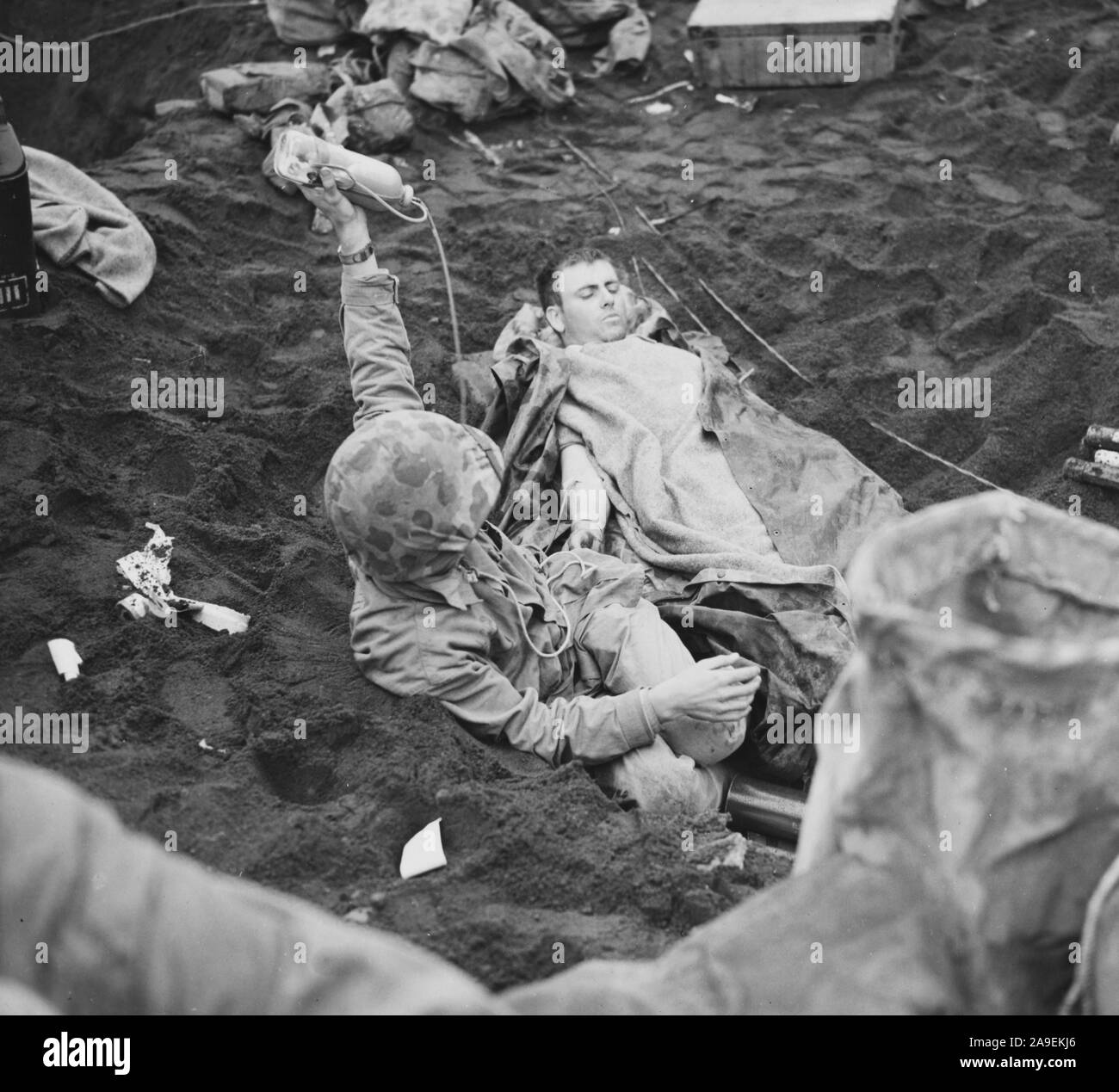 Un oficial de la naval adminsiters plasma sanguíneo a un soldado herido en Iwo Jima Foto de stock