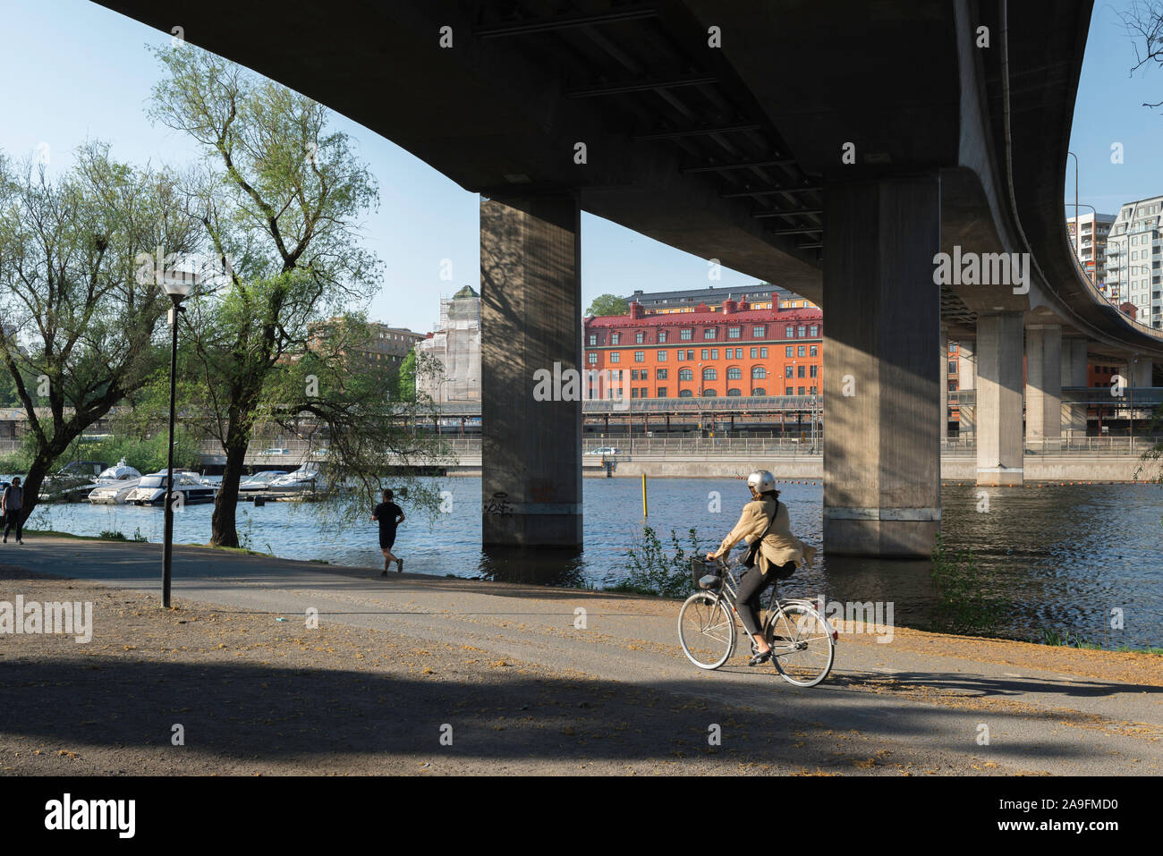 Río de la ciudad de Estocolmo, la vista de una mujer en bicicleta junto a Klara Sjö, un río estrecho que separa el Kungsholmen y Norrmalm distritos de Estocolmo, Suecia. Foto de stock