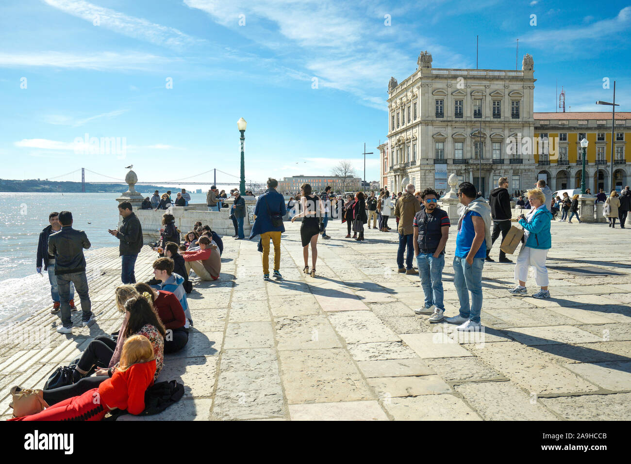 Europa, Portugal, Lisboa, Junge Leute sitzen an der Uferpromenade am Fluss Tejo Foto de stock