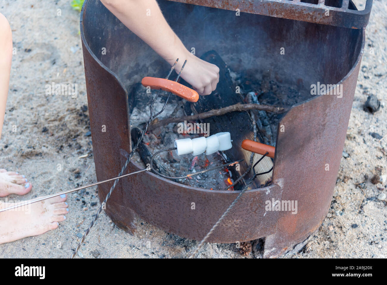 Close-up de malvaviscos y hot dogs a asar palos cocinar en fogata en playa en verano Foto de stock