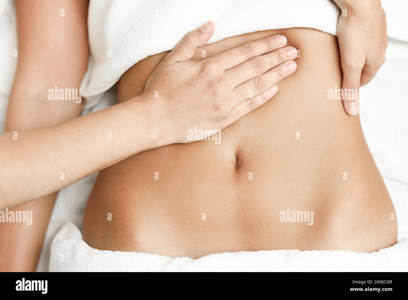 Manos abdomen femenino.terapeuta de masaje aplicando presión sobre el vientre. Foto de stock