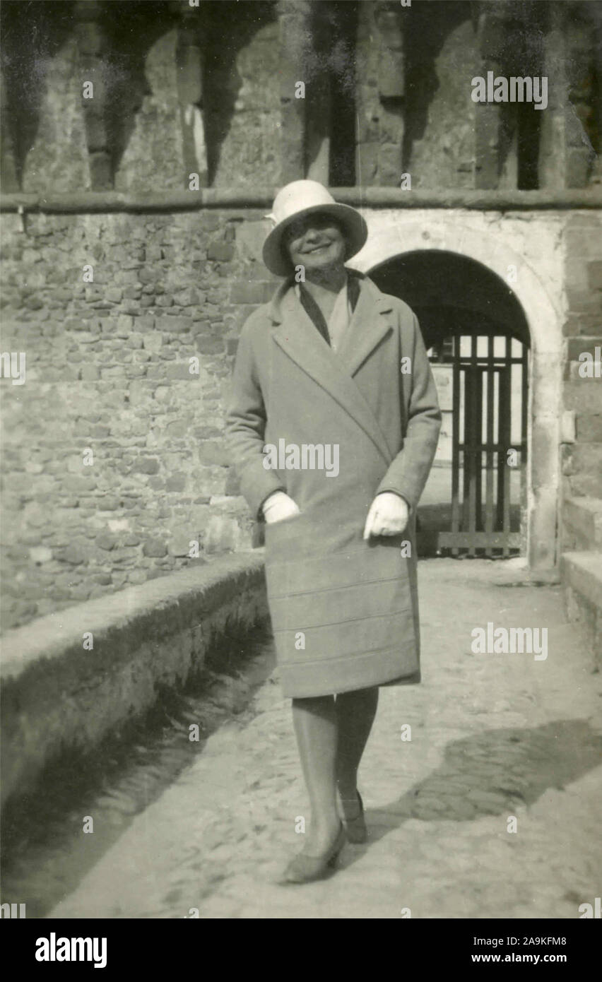 Una mujer con sombrero y abrigo a rayas cerca de la entrada de un castillo, Italia Foto de stock