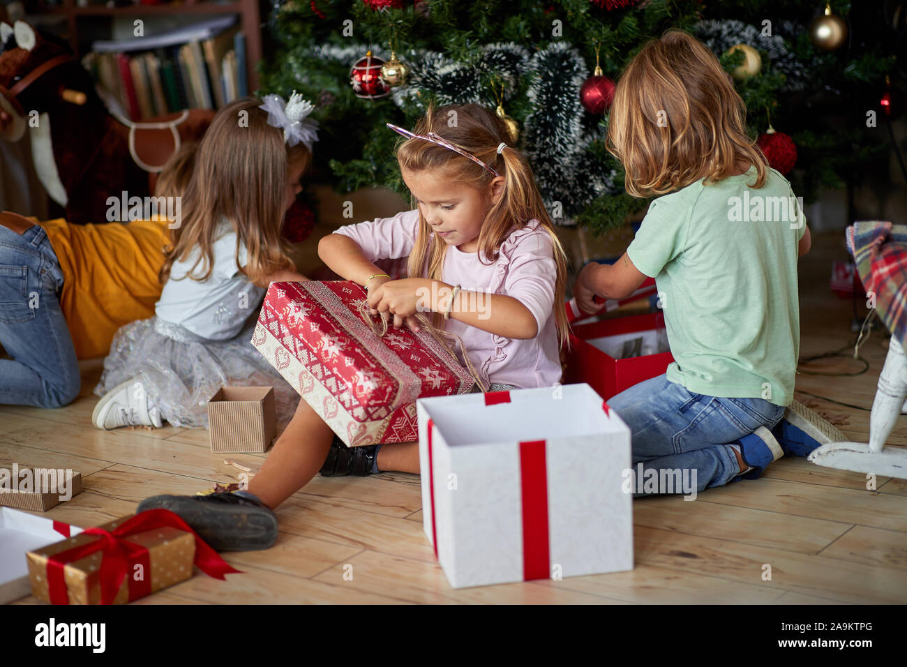 Los niños abriendo regalos de Navidad. Niño lindo bajo el árbol de Navidad  con cajas de regalo Fotografía de stock - Alamy