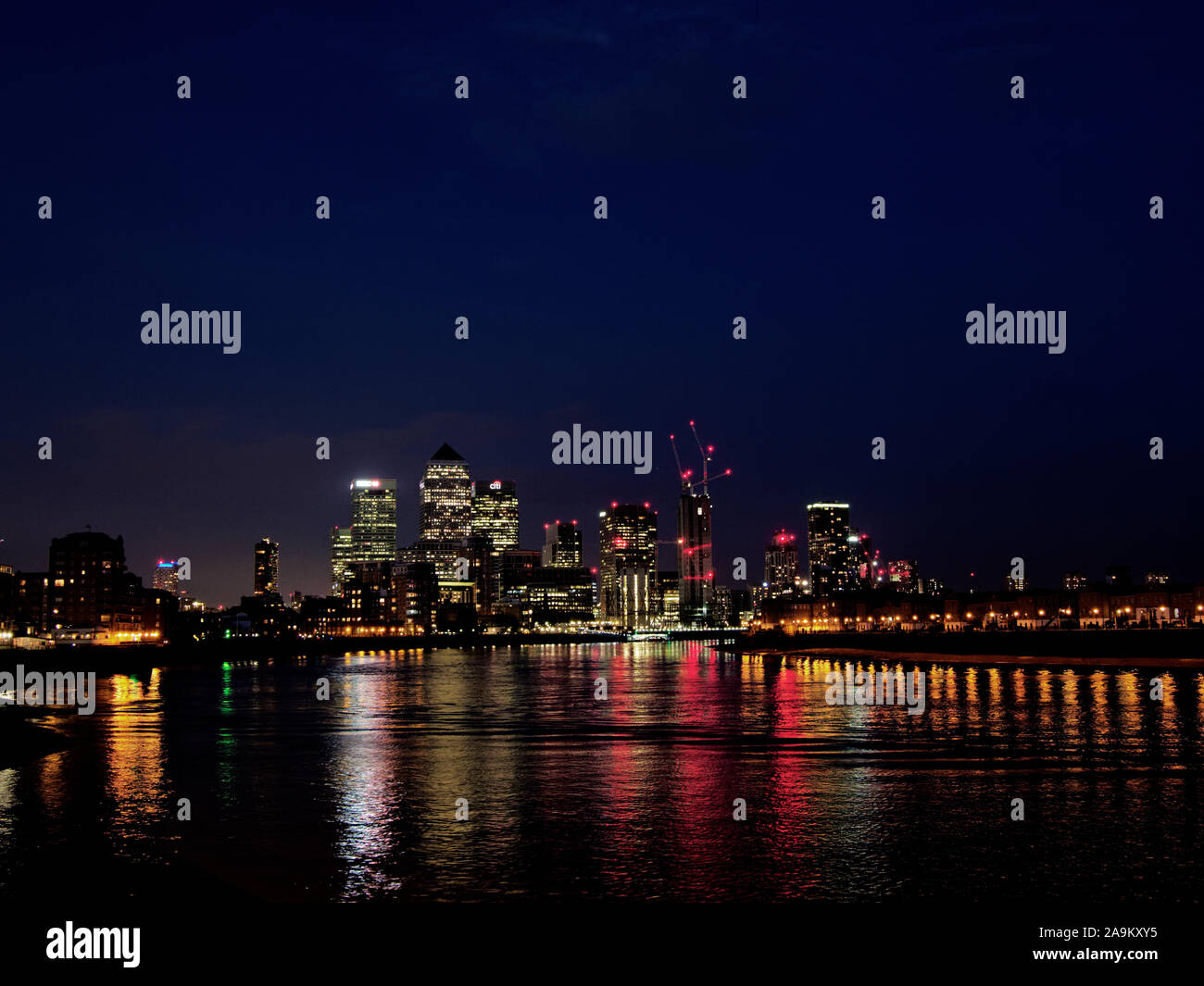 Vista sobre el horizonte de Canary Wharf y Rotherhithe por la noche desde LImehouse cruzando el río Támesis Foto de stock