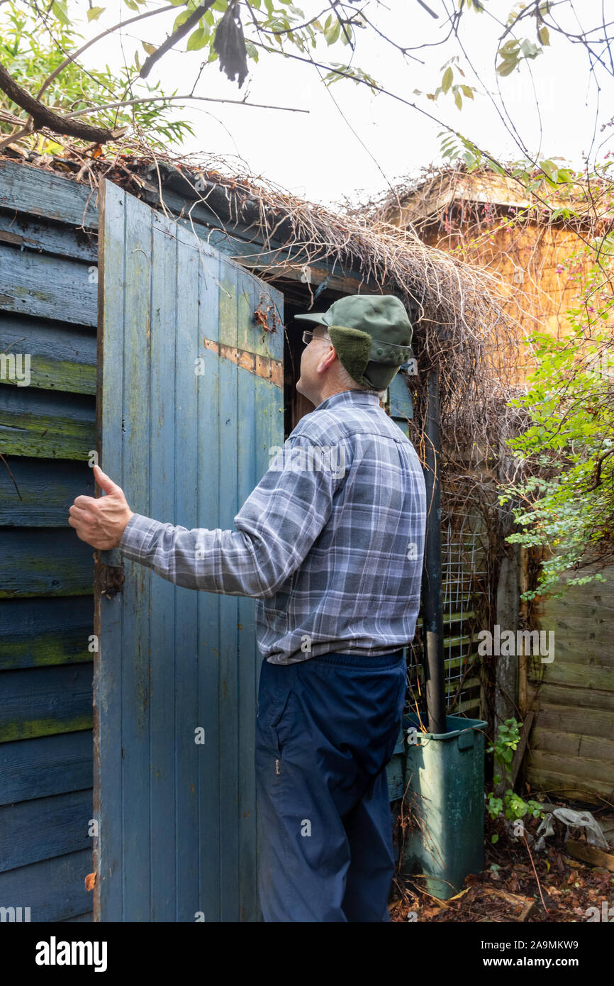 Hombre de demoler un antiguo cobertizo de jardín de madera - Extracción de la puerta Foto de stock