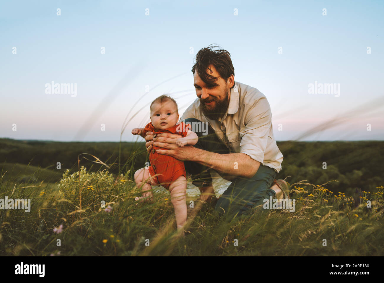 Padre de familia feliz y el bebé camina sobre el césped outdoors lifestyle papá y niño hija juntas las vacaciones de verano la paternidad niñez concepto padre Foto de stock