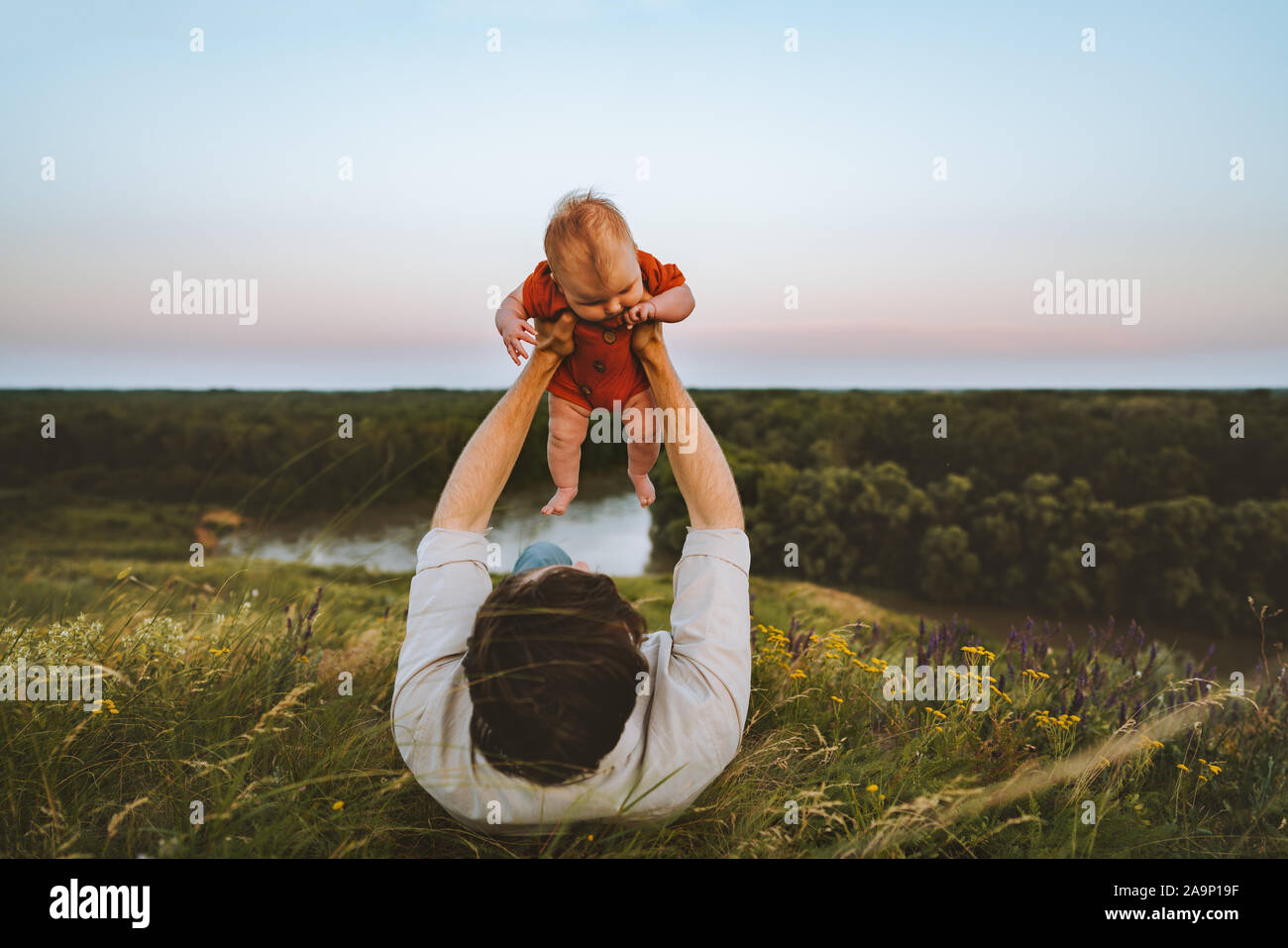 Padre e hija recostada sobre la hierba al aire libre estilo de vida familiar papá y bebé niño caminando juntos las vacaciones de verano la paternidad niñez concepto Foto de stock