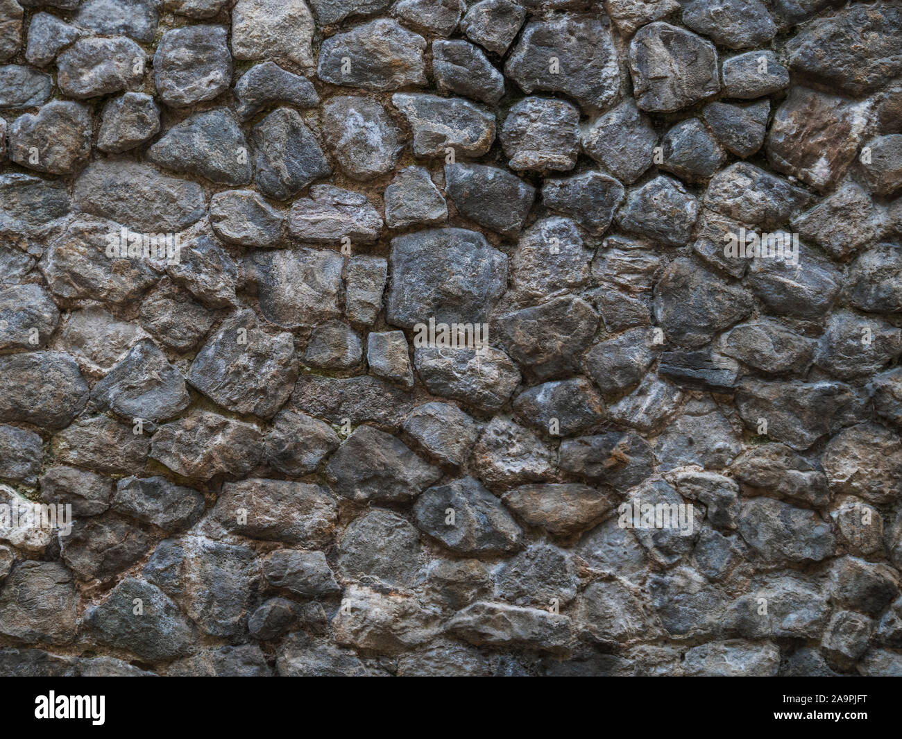 Muro de piedra oscura de adoquines ásperos. Foto de stock