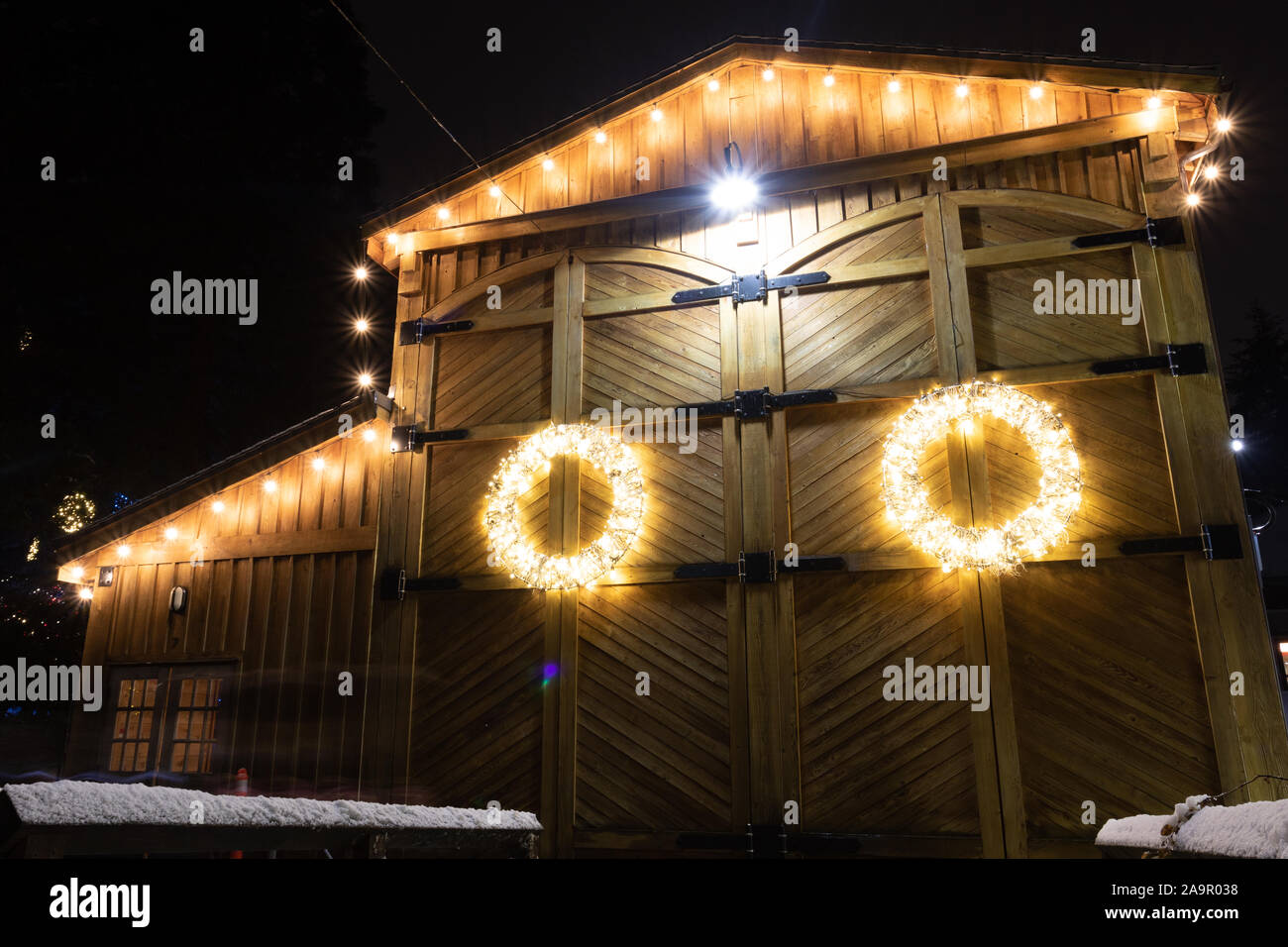 Barn House está decorado con luces de Navidad fotografiado en una noche de invierno, esta ofrenda floral se destaca contra el fondo de madera desgastada. Foto de stock