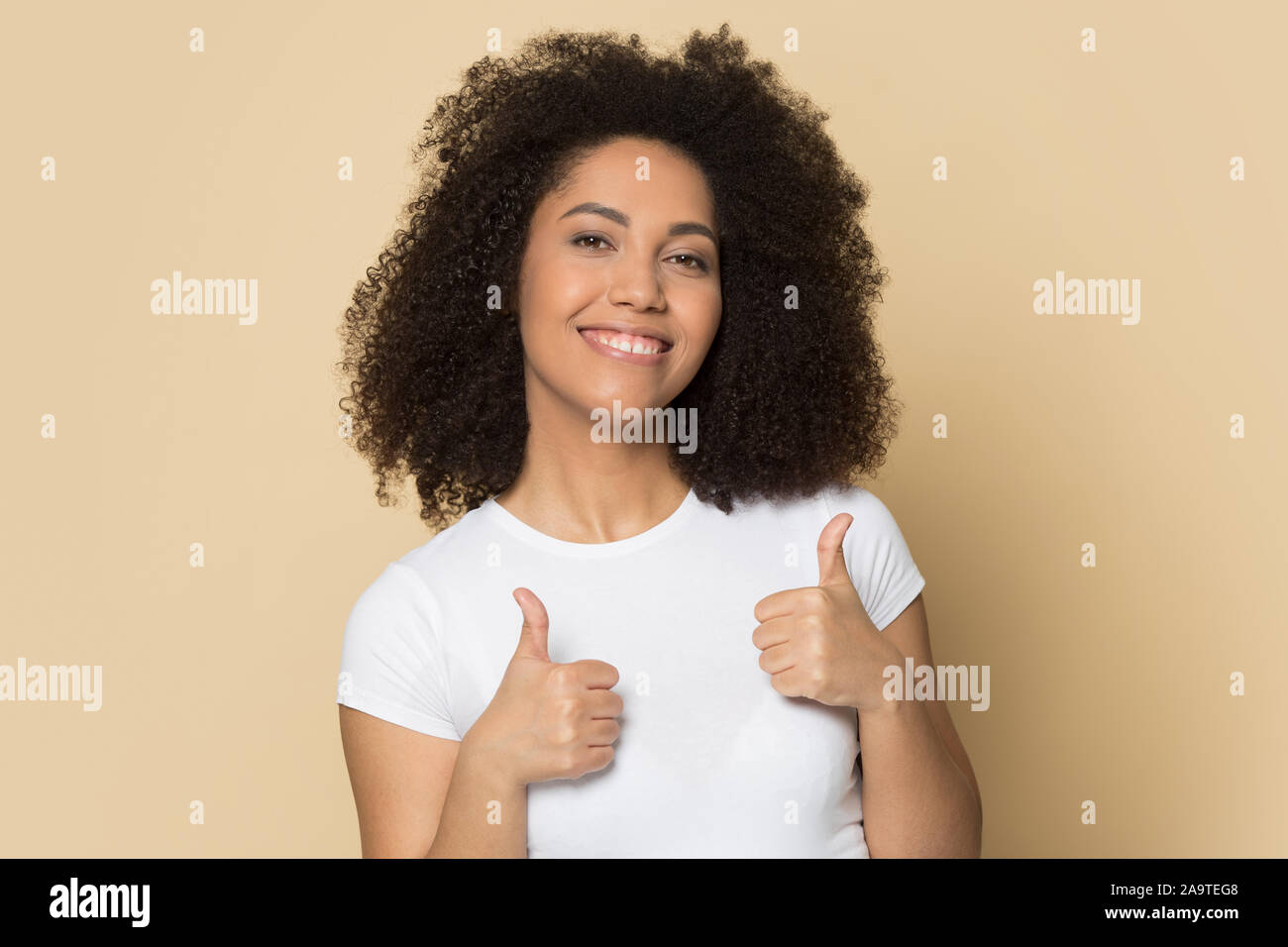 Hermosa chica americana africana con sonrisa saludable mostrando Thumbs up Foto de stock