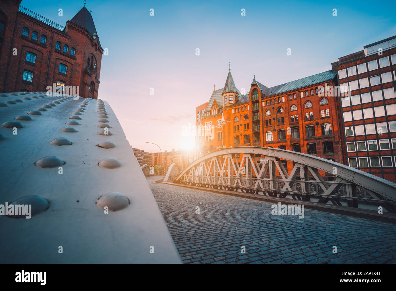 Arco de hierro puentes históricos en almacenes en distrito Speicherstad en Hamburgo, Alemania. Sun retroiluminado bengalas luminosas. Foto de stock