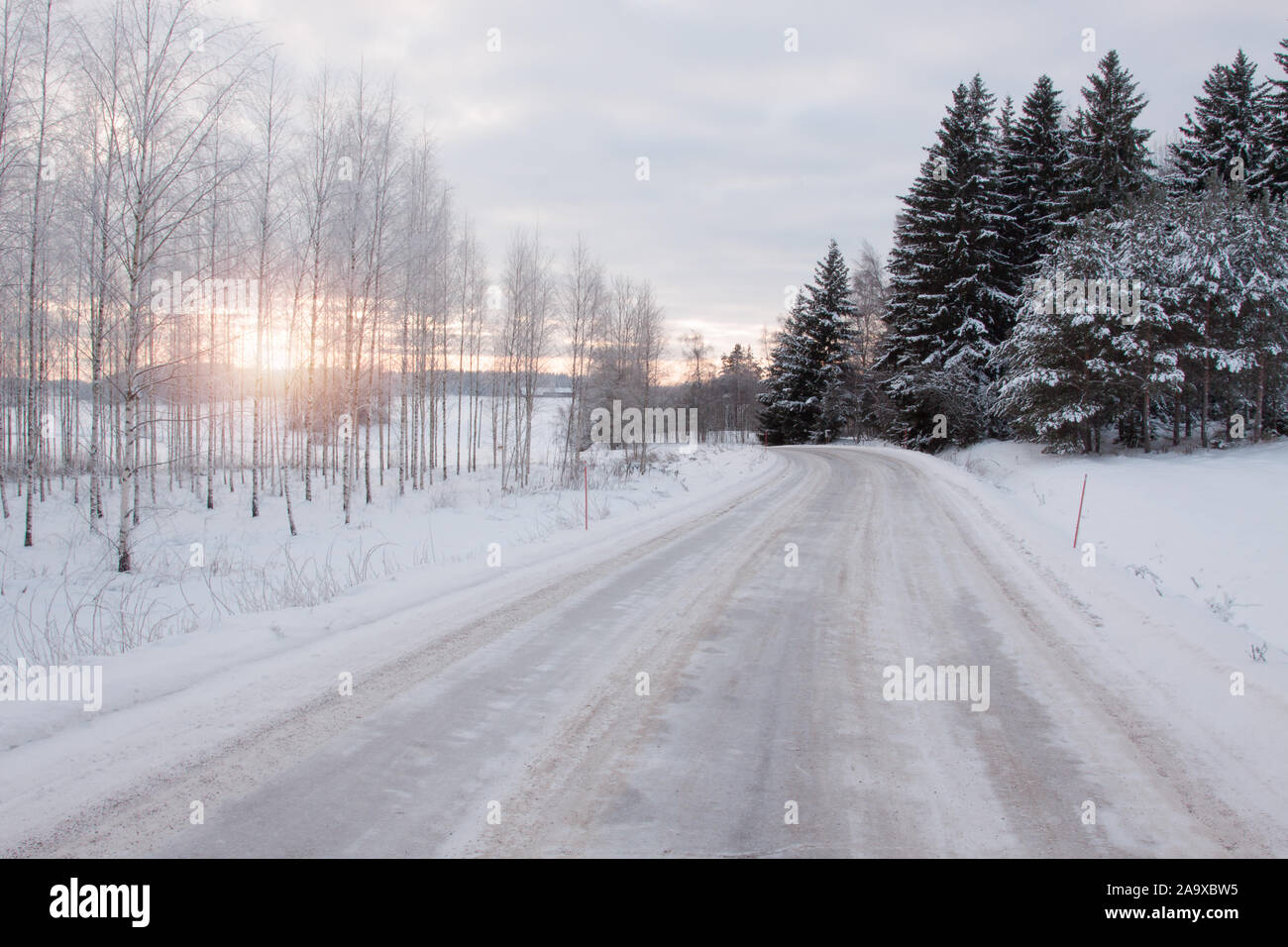 Paisaje invernal con heladas y nieve en los árboles. La nieve se encuentra junto a la carretera de arado profundo. Salo, Finlandia. Foto de stock