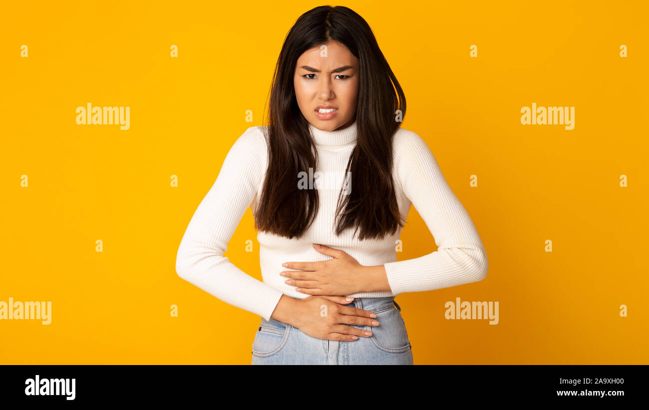 Chica asiática con dolor de estómago tras intoxicación alimentaria Foto de stock