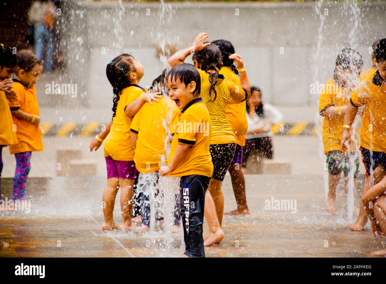 Niños felices jugando en la fuente de agua Foto de stock