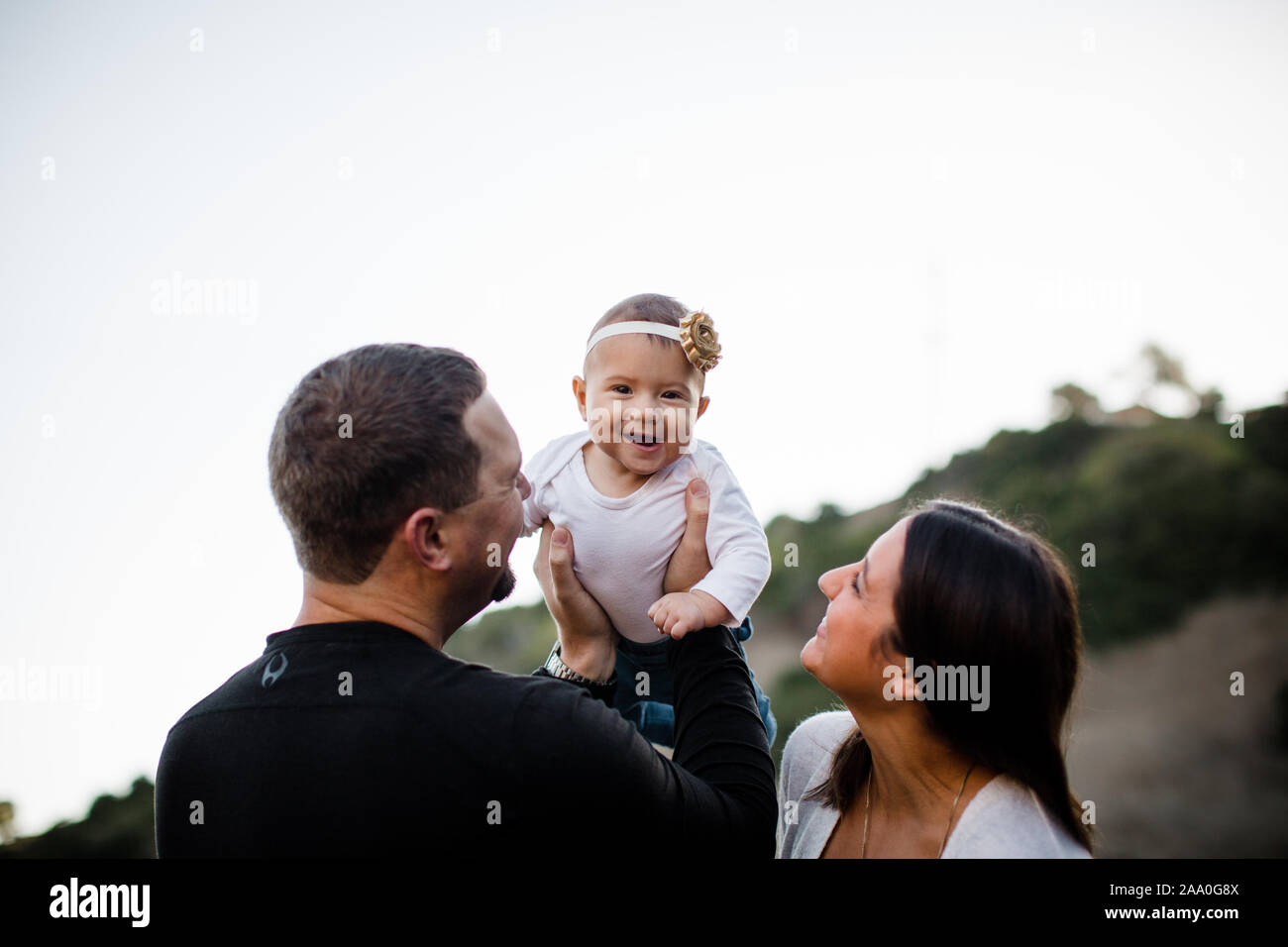 Papá Levante hija infante como risas de bebé & Mamá relojes Foto de stock