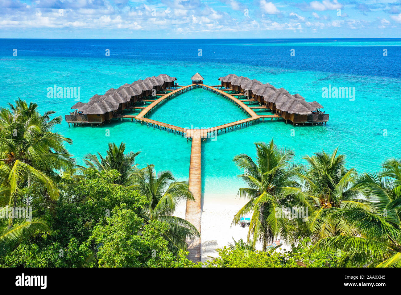 Vista aérea de la isla tropical paradisíaca lujosas villas de agua dentro de los arrecifes de coral de agua azul turquesa y la laguna rodeada de palmeras Foto de stock