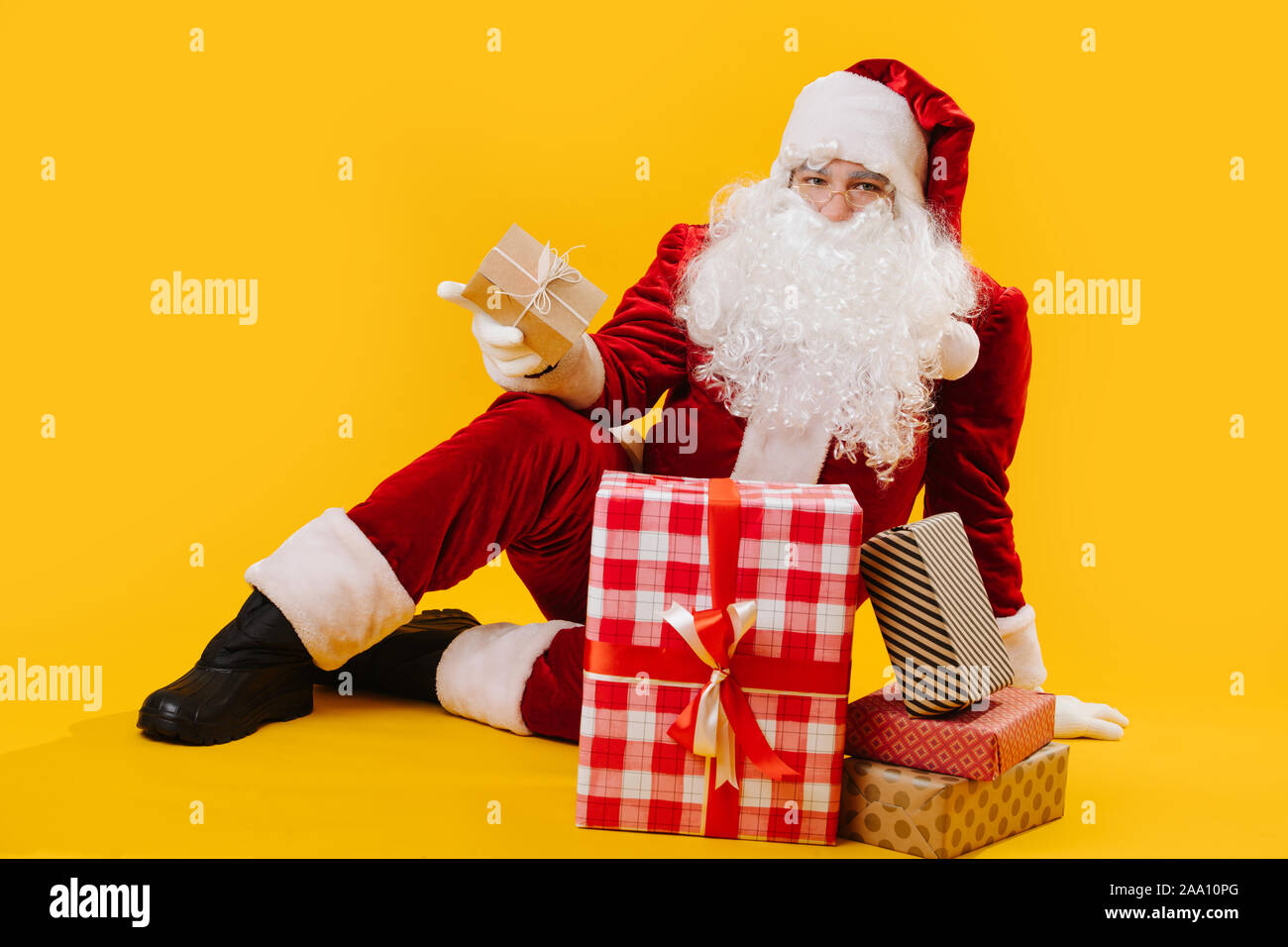 Retrato de Santa sentados en el suelo en el studio, sosteniendo un cuadro en su mano Foto de stock