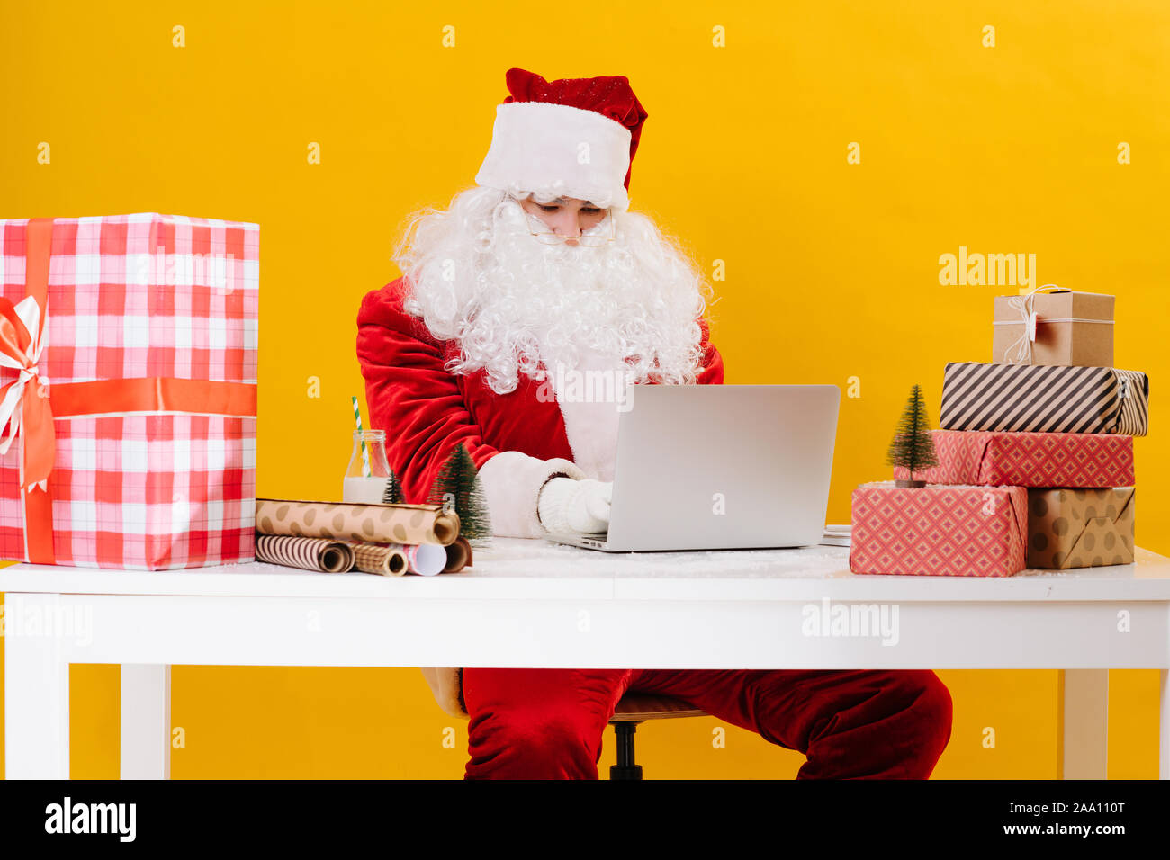 Santa Claus se sienta en una mesa, acepta correos y prepara los regalos de Navidad Foto de stock