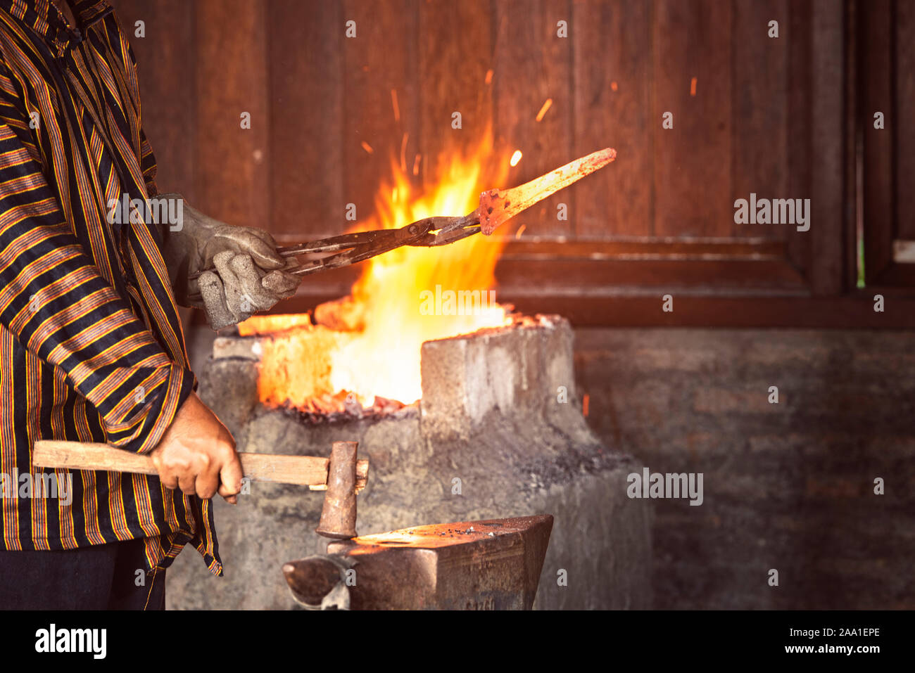 Herrero forja un hierro candente en la forja. martillo de forja de  estructuras metálicas en un yunque de hierro fundido al aire libre en la  naturaleza Fotografía de stock - Alamy