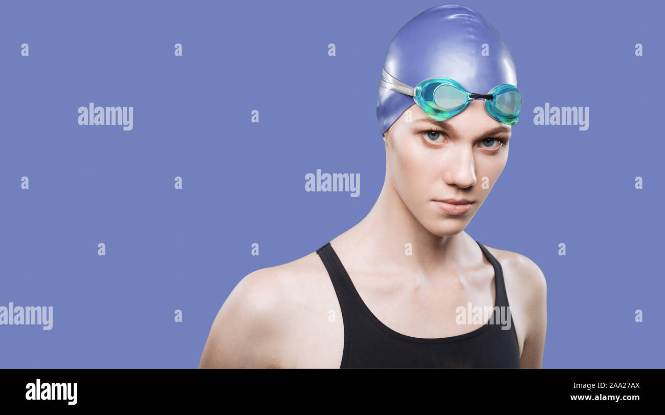 Mujer nadadora en natación gorra y gafas mira a la cámara a través de antecedentes aislados Foto de stock