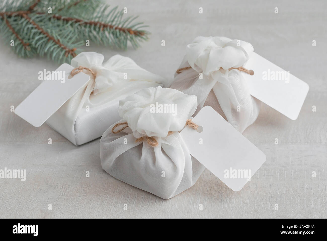 Regalo de navidad envuelto con tela furoshiki blanco con etiquetas. Eco friendly regalo. Foto de stock