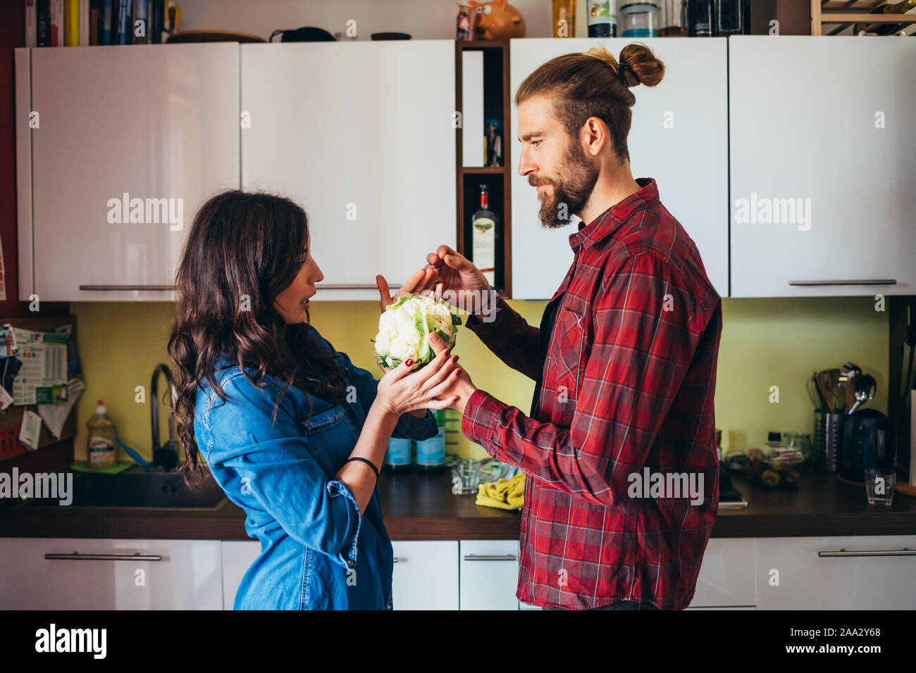 Afectuosa pareja joven cocinar las verduras en la cocina en casa - vegan, saludables, concepto de trabajo en equipo Foto de stock