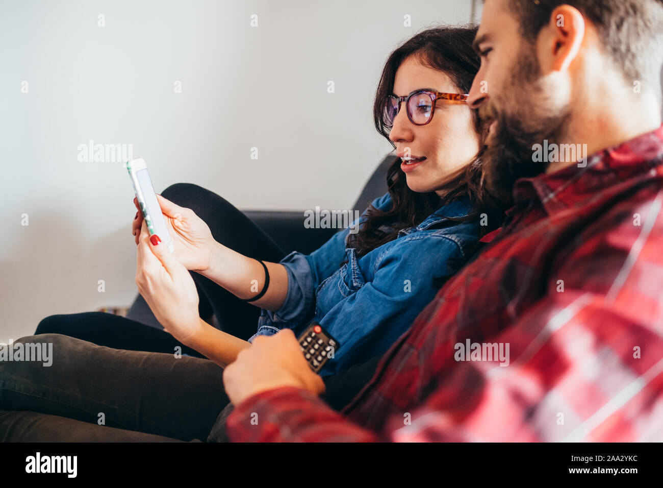 Pareja joven sofá indoor en casa mirando smartphones - streaming de vídeo, la tecnología, el concepto de entretenimiento Foto de stock