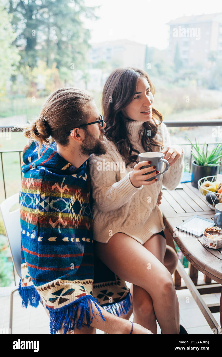 Pareja joven en casa terraza desayunando - ella está sentado en su regazo, amor, relación, romance concepto Foto de stock