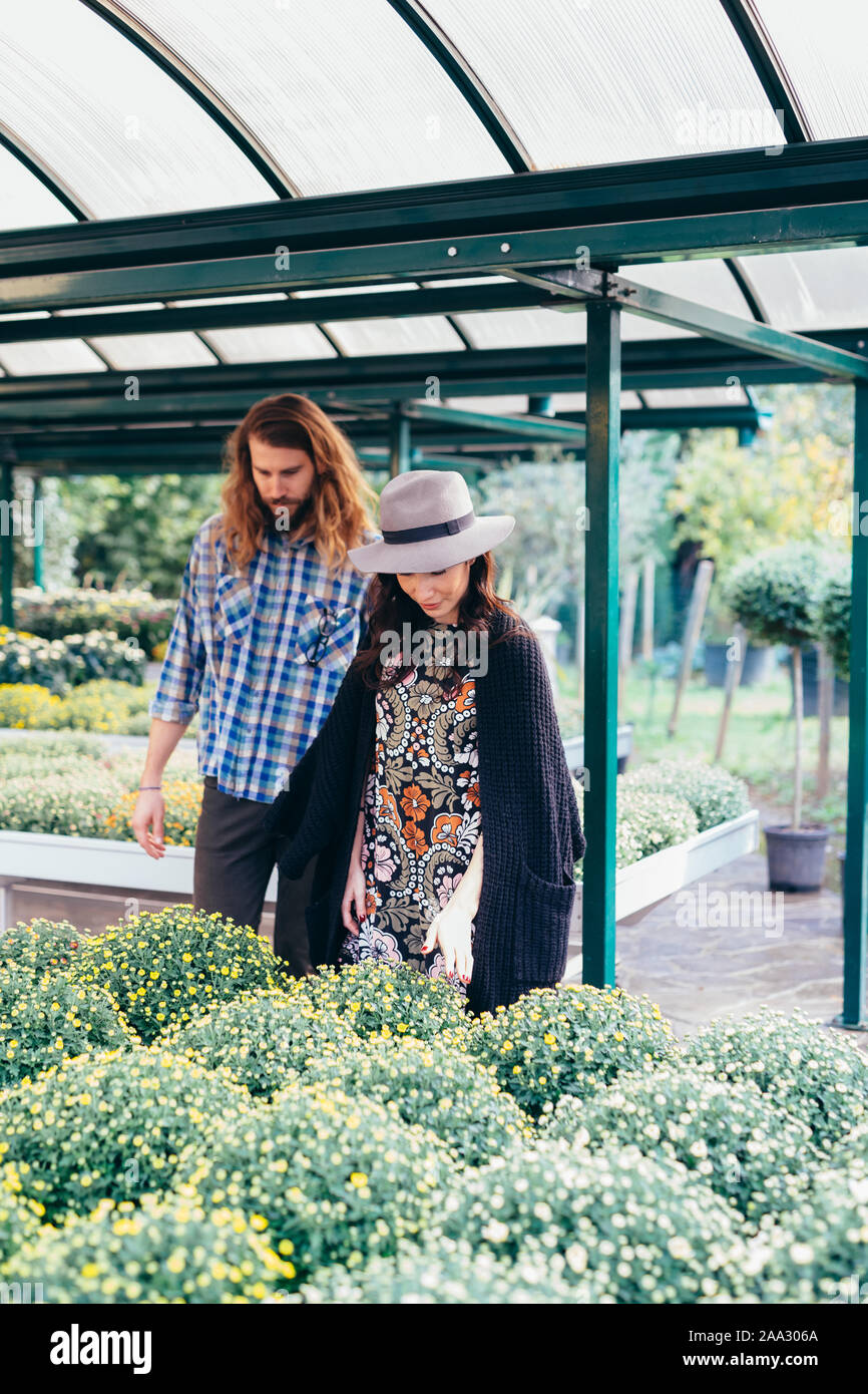 Hermosa joven pareja feliz juntos greenhouse - Blooming, la jardinería, el concepto de naturaleza Foto de stock