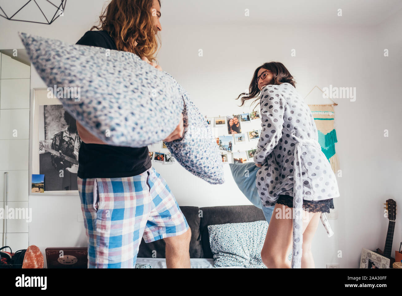Joven pareja feliz almohada playfighting dormitorio interior - divertirse jugando, concepto positivo Foto de stock