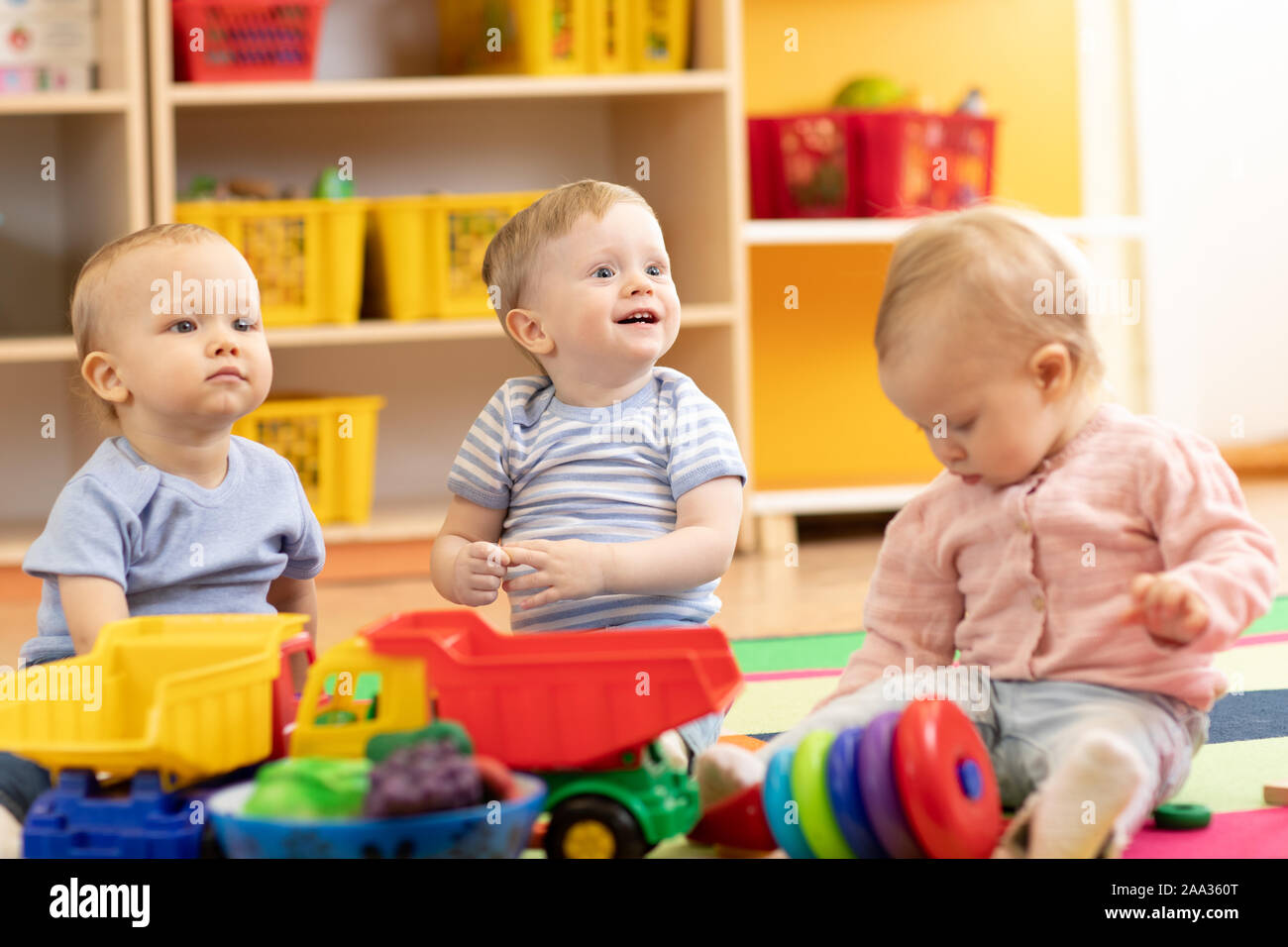 Poco bebés niños y una niña jugando juntos en el kinder o guardería. Niños en edad preescolar en guarderías Foto de stock
