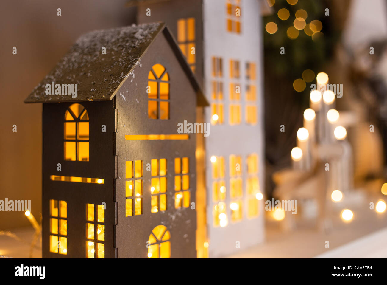 Primer plano de casas de papel con luces dentro de pie sobre fondo de otras decoraciones. El enfoque selectivo. Foto de stock