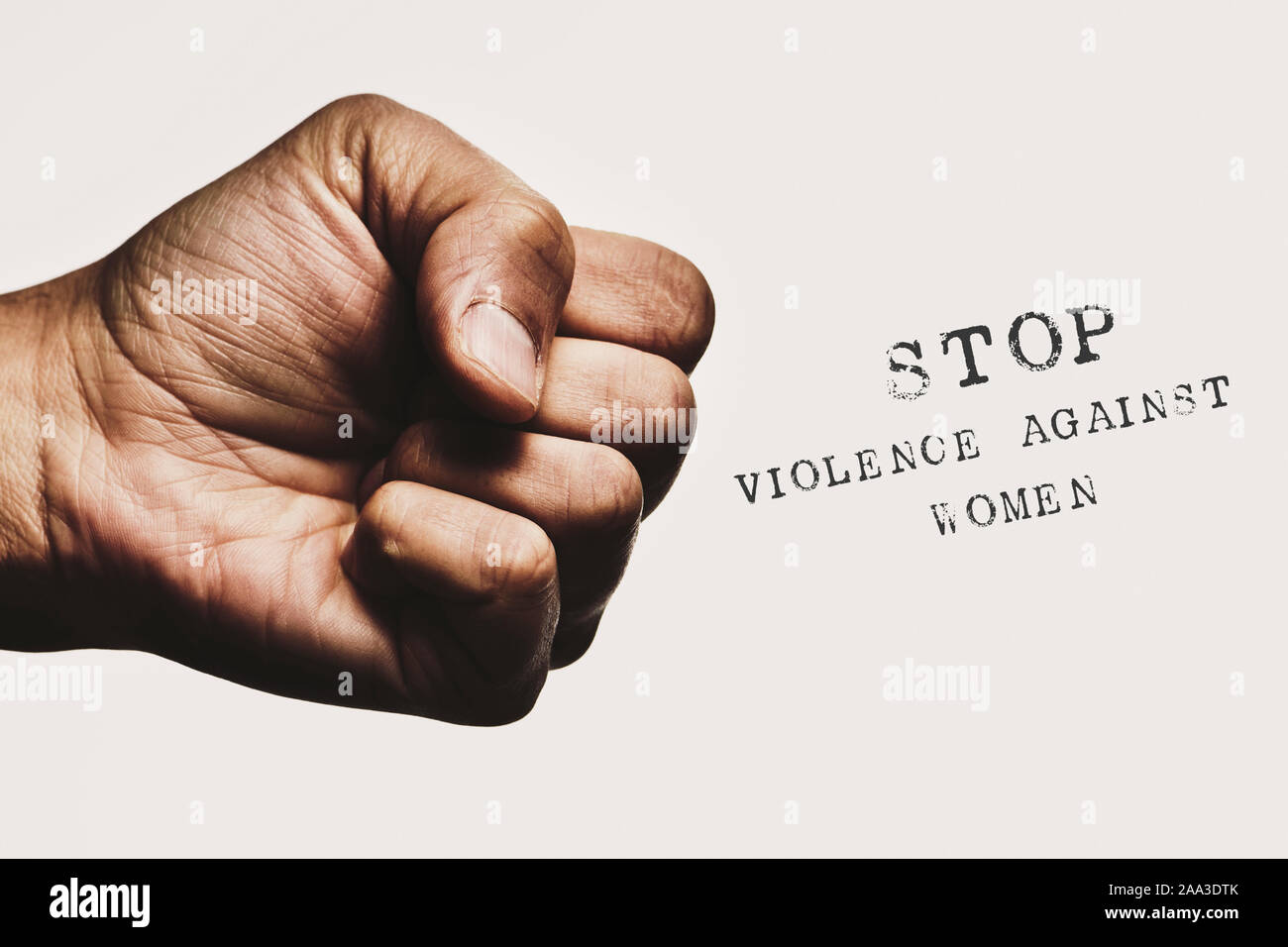 Primer plano de un hombre con el puño cerrado y amenazante el texto detener la violencia contra la mujer, contra un fondo blanco. Foto de stock