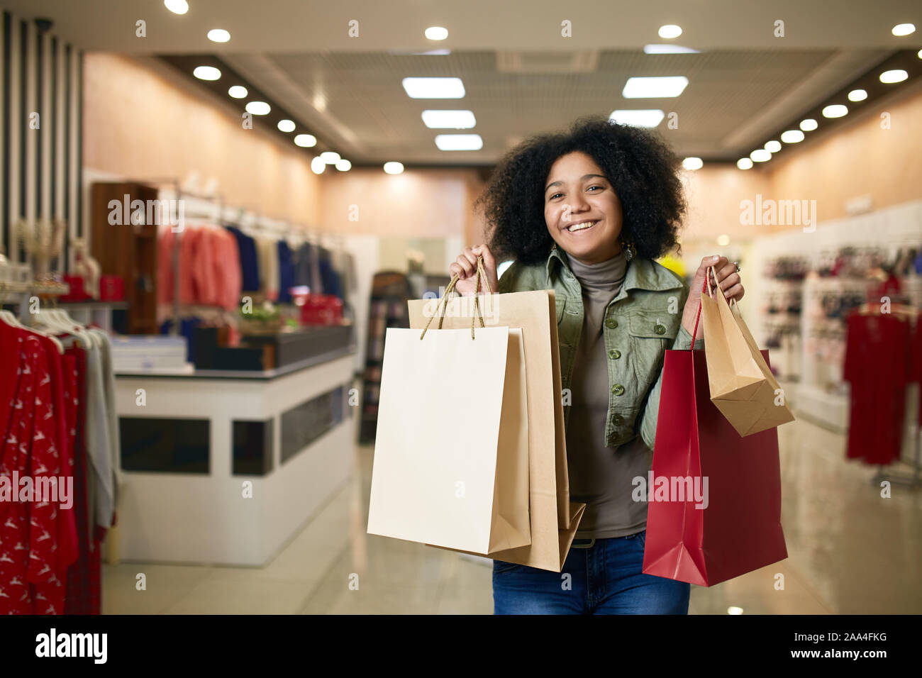 Atractivo lindo joven afroamericana posando con bolsas de compras tiendas de ropa en el fondo. Bonita chica negra shopper feliz con ella de - Alamy