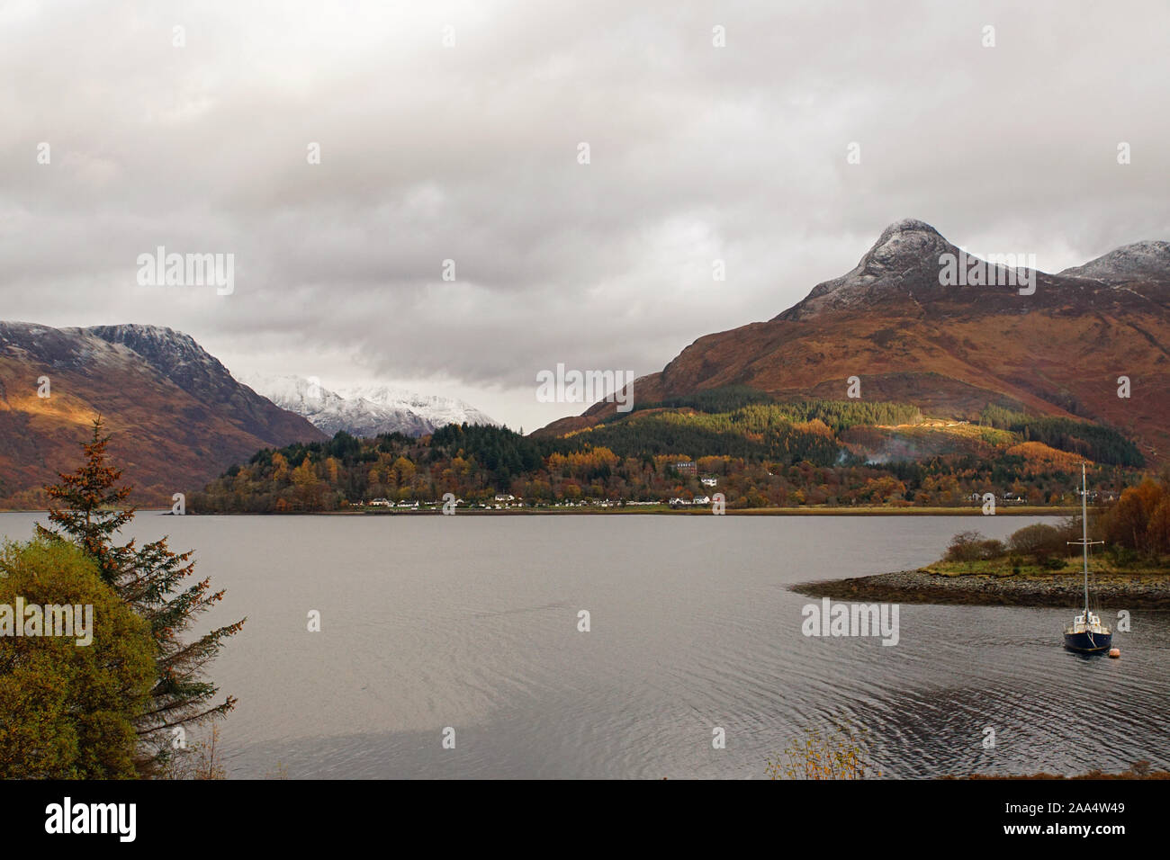 Loch Leven hacia Invercoe Village y la nieve rematada Pap de Glencoe con el lago en primer plano Foto de stock