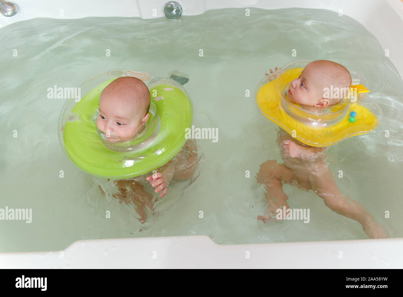 Nacido gemelos nadando en la bañera o bañera. Círculo inflable les ayuda a  permanecer en la superficie del agua. Endurecimiento y de estilo de vida  saludable Fotografía de stock - Alamy