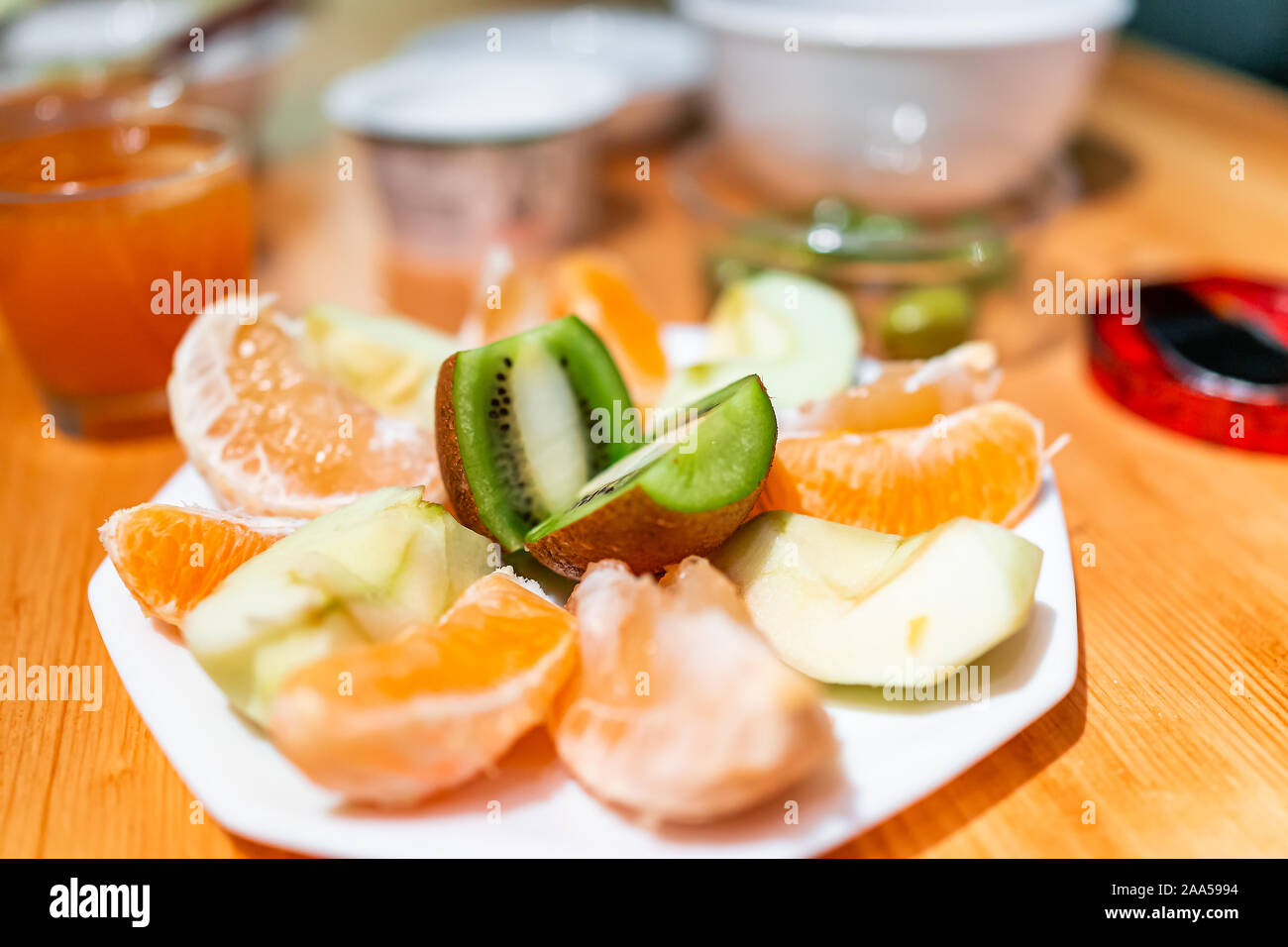 Placa blanca de los alimentos agrios rodajas de fruta en mesa de madera para desayuno con kiwi, manzana verde y grapefuit Foto de stock