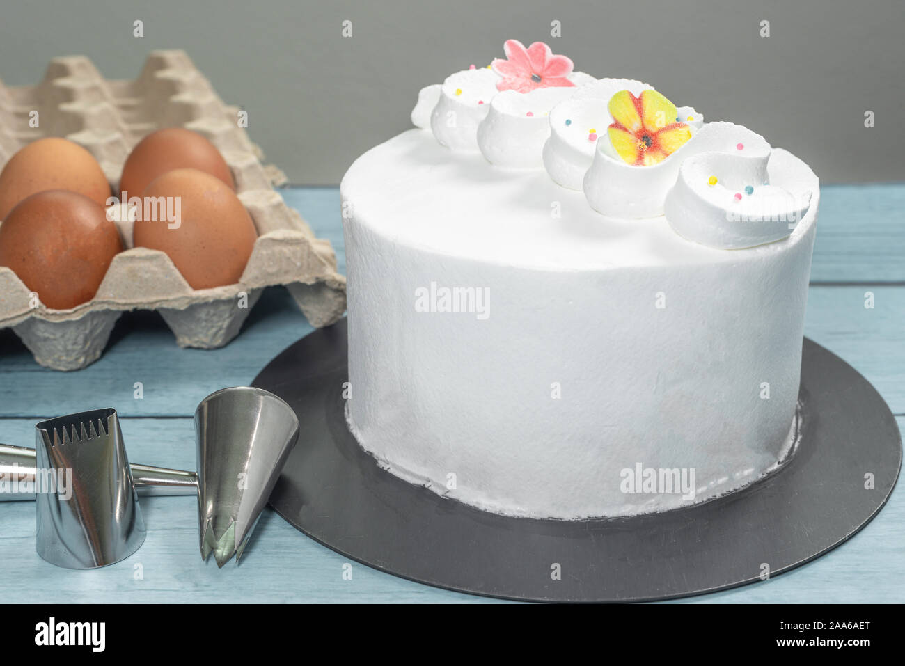 Pastel glaseado, haciendo accesorios y utensilios para hornear huevos crudos en la mesa de la cocina Foto de stock