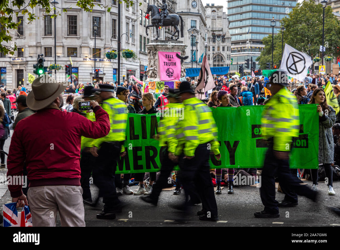 Londres, Inglaterra, Reino Unido - 10 de octubre de 2019: un turista toma una fotografía de una extinción rebelión protesta en Trafalgar Square en Londres central. Foto de stock