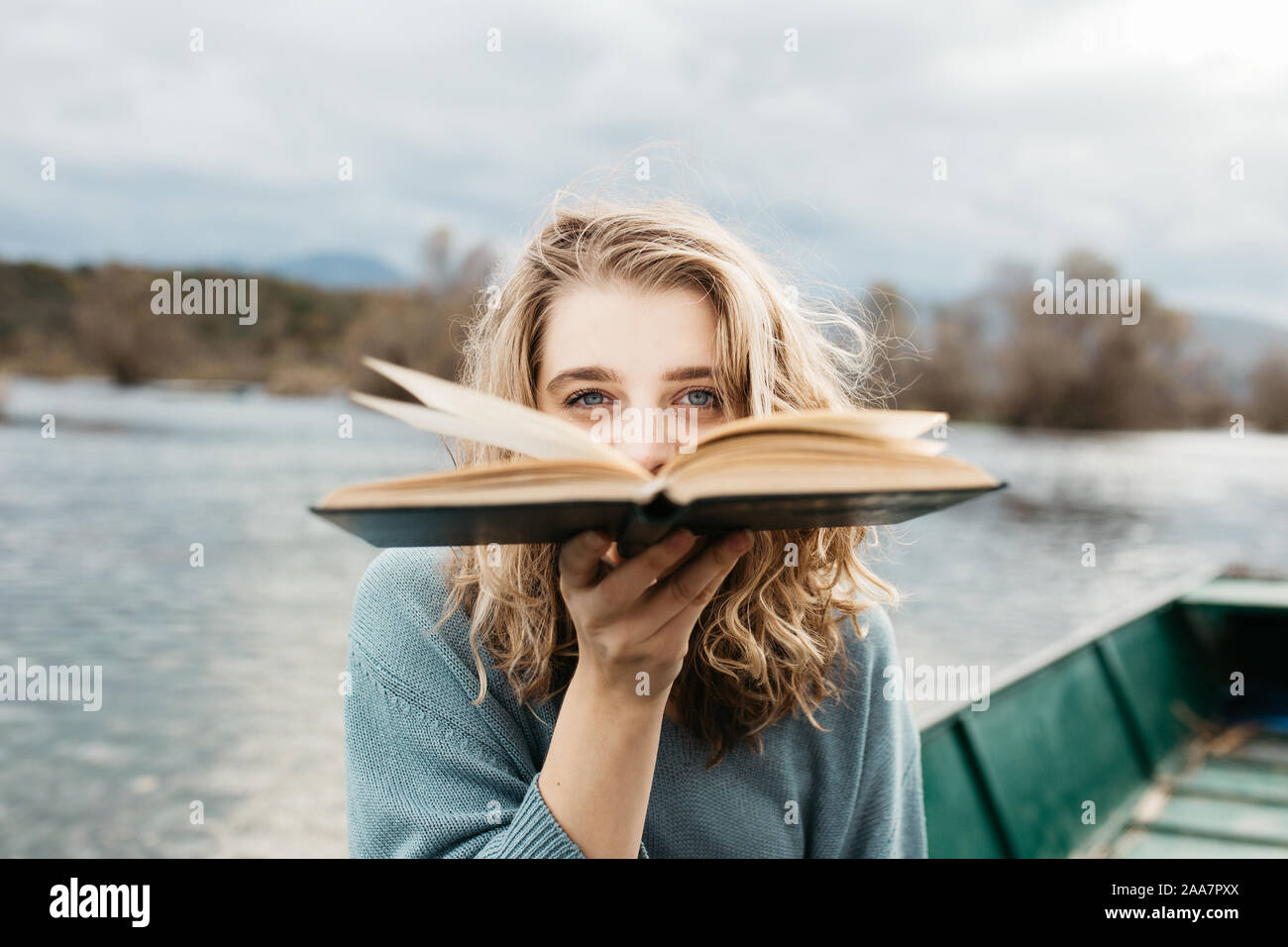 Retrato de una joven hermosa mujer sentada en un barco y leyendo un libro. Ella es una lombriz y ella elige entre pocos libros. Foto de stock