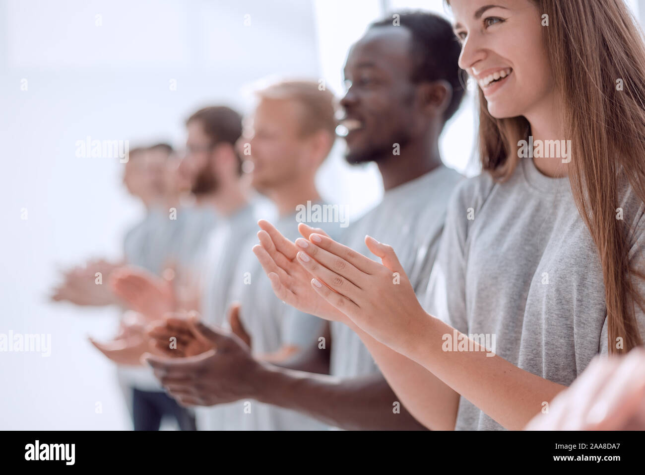 Imagen de un grupo de jóvenes de pie en una fila aplaudiendo. Foto de stock