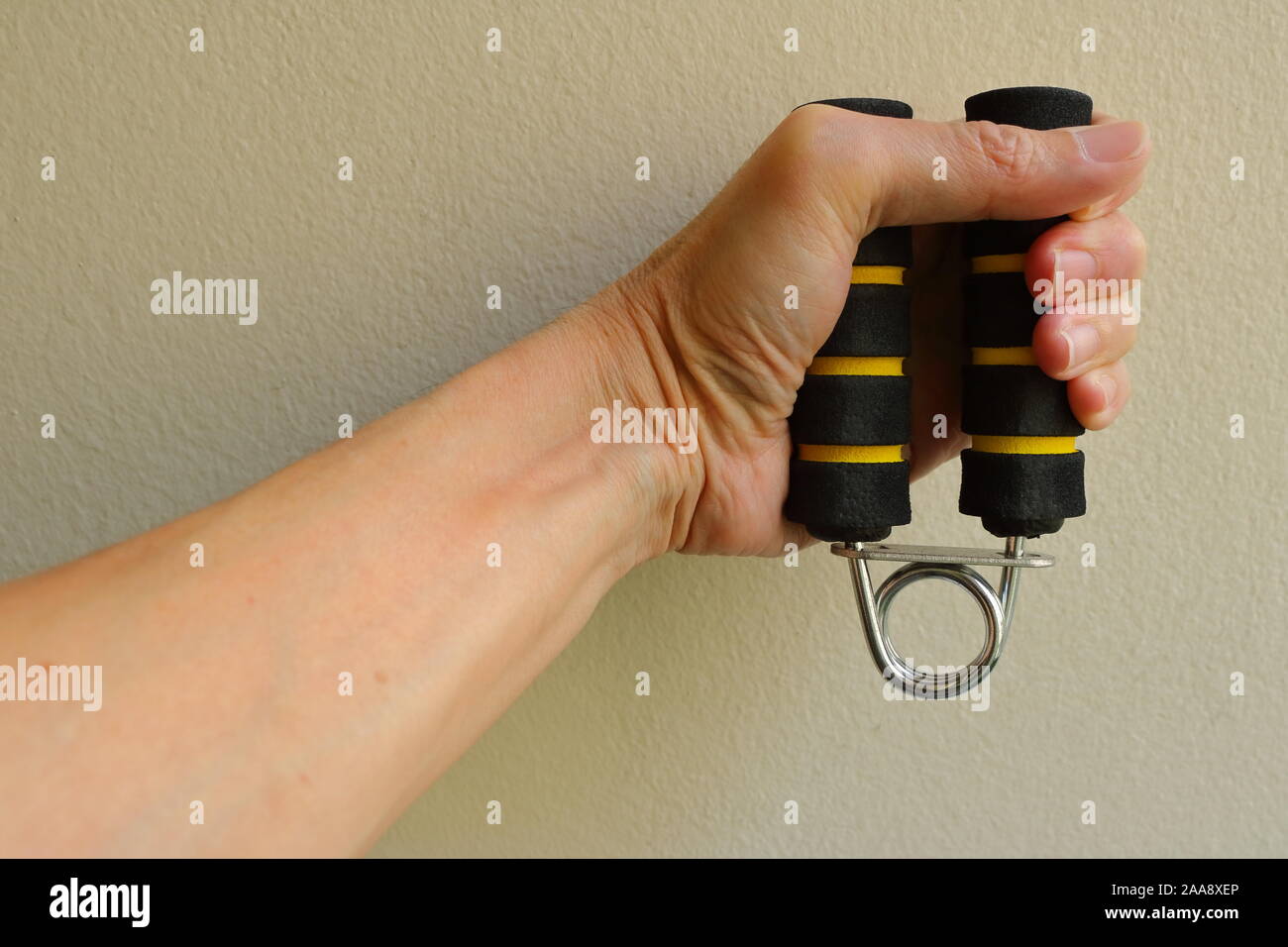 Closeup mano izquierda sosteniendo y apretando la mano riostras, esta herramienta puede ser usada para aliviar la tensión y mejorar la capacidad de alimentación de mano Foto de stock