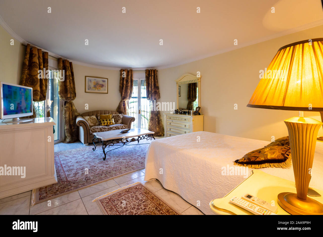 Dormitorio en estilo clásico, mobiliario, iluminación suave. Foto de stock