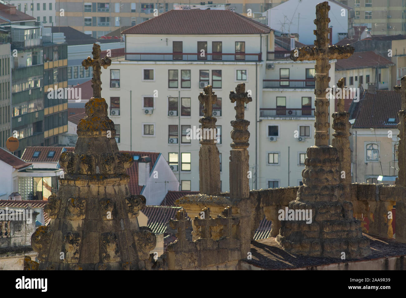 Cruces de piedra en la iglesia de Santa Cruz con modernos edificios en el fondo en Coimbra Portugal Foto de stock