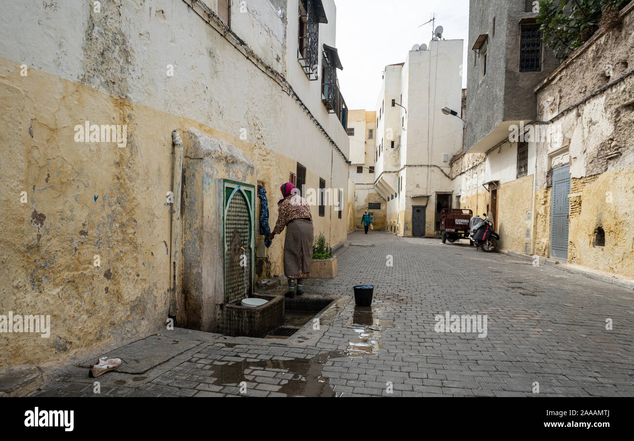 Fez, Marruecos. El 9 de noviembre de 2019. Una mujer lavando la ropa en una fuente pública en las calles de la medina. Foto de stock