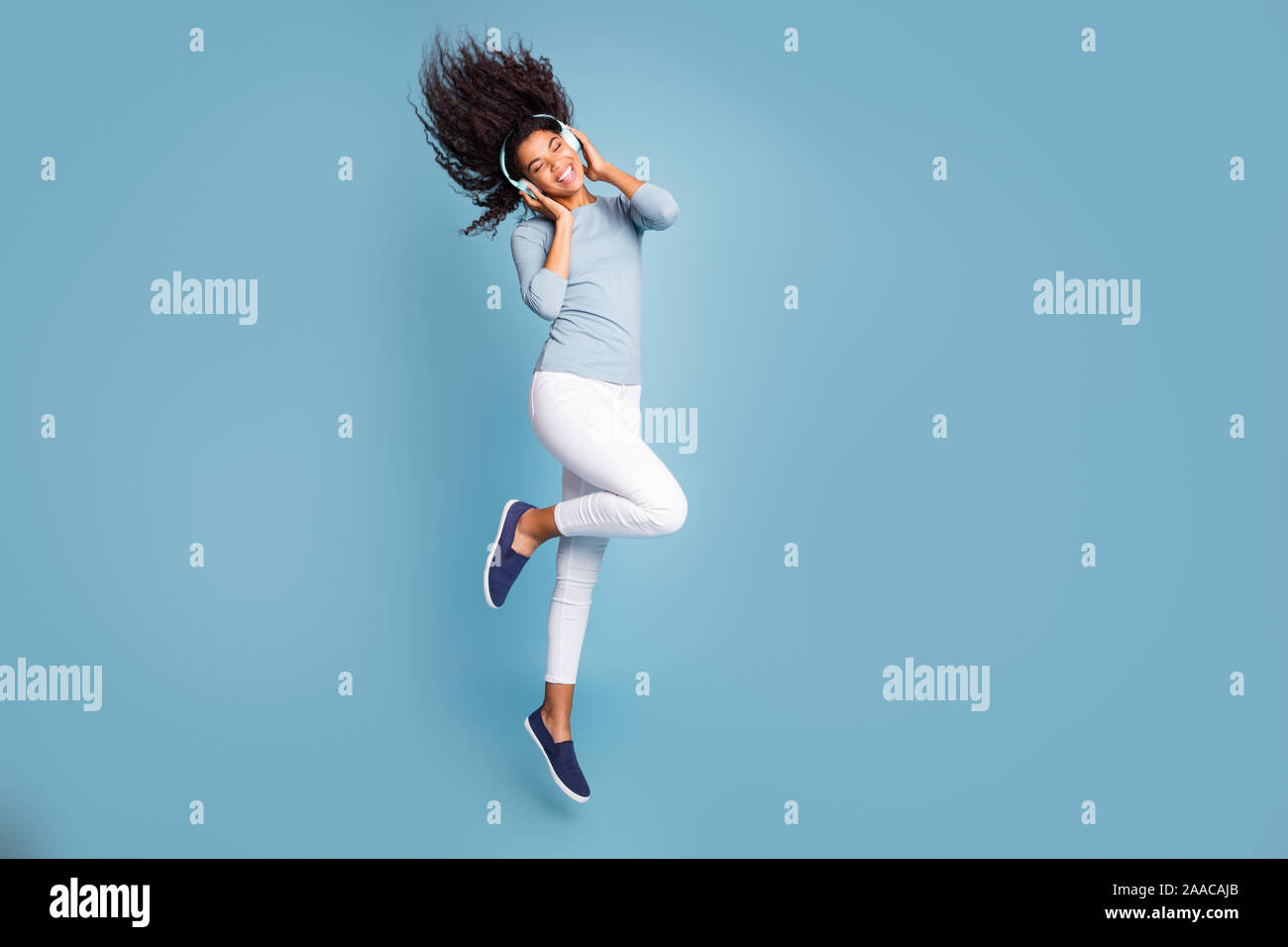 Volcó toda su longitud el tamaño del cuerpo foto de alegre cute nice positivos dulce chica escuchando música en auriculares saltando con el cabello volando pastel aislado Foto de stock